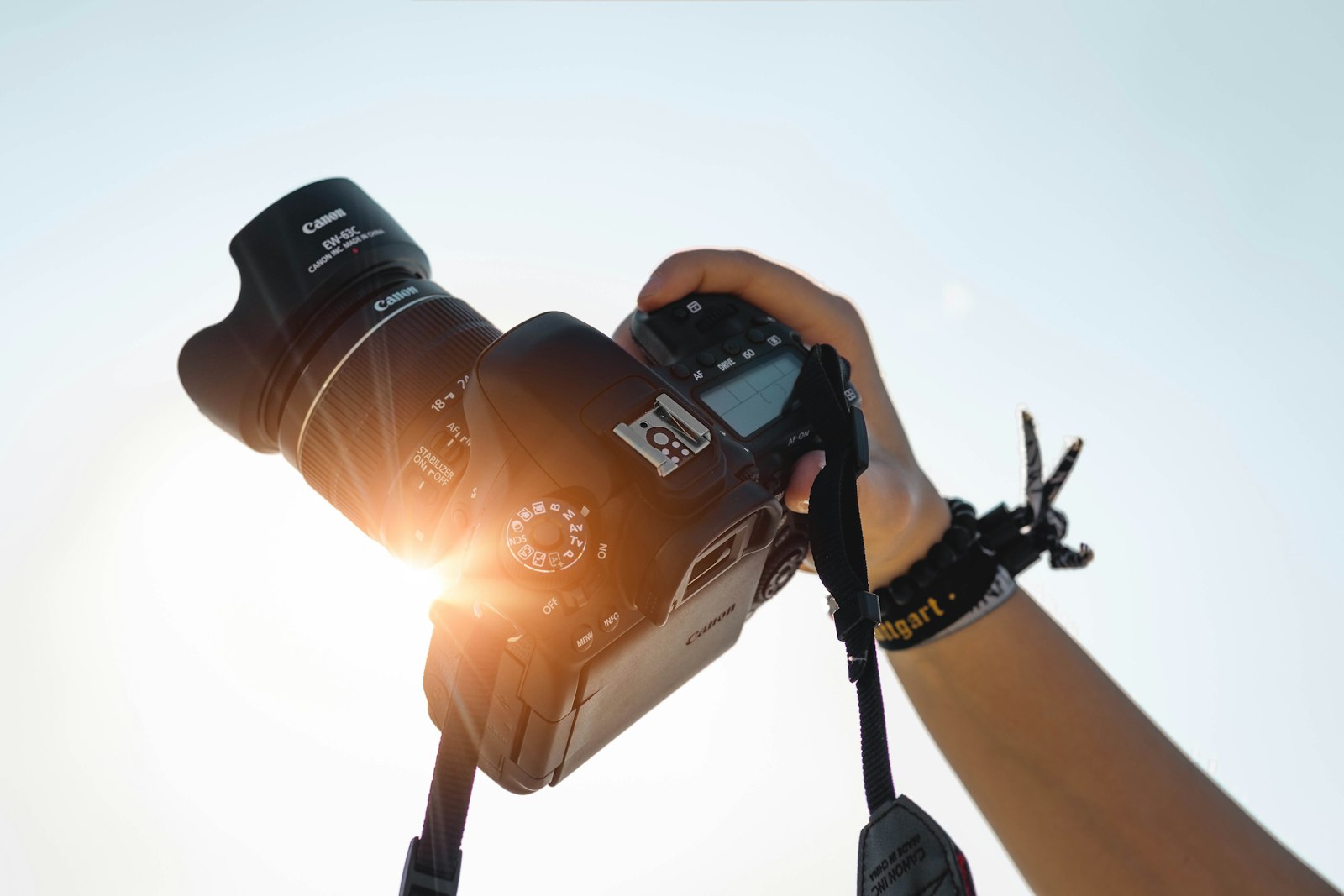 Photographer's hand holding a camera against the sky