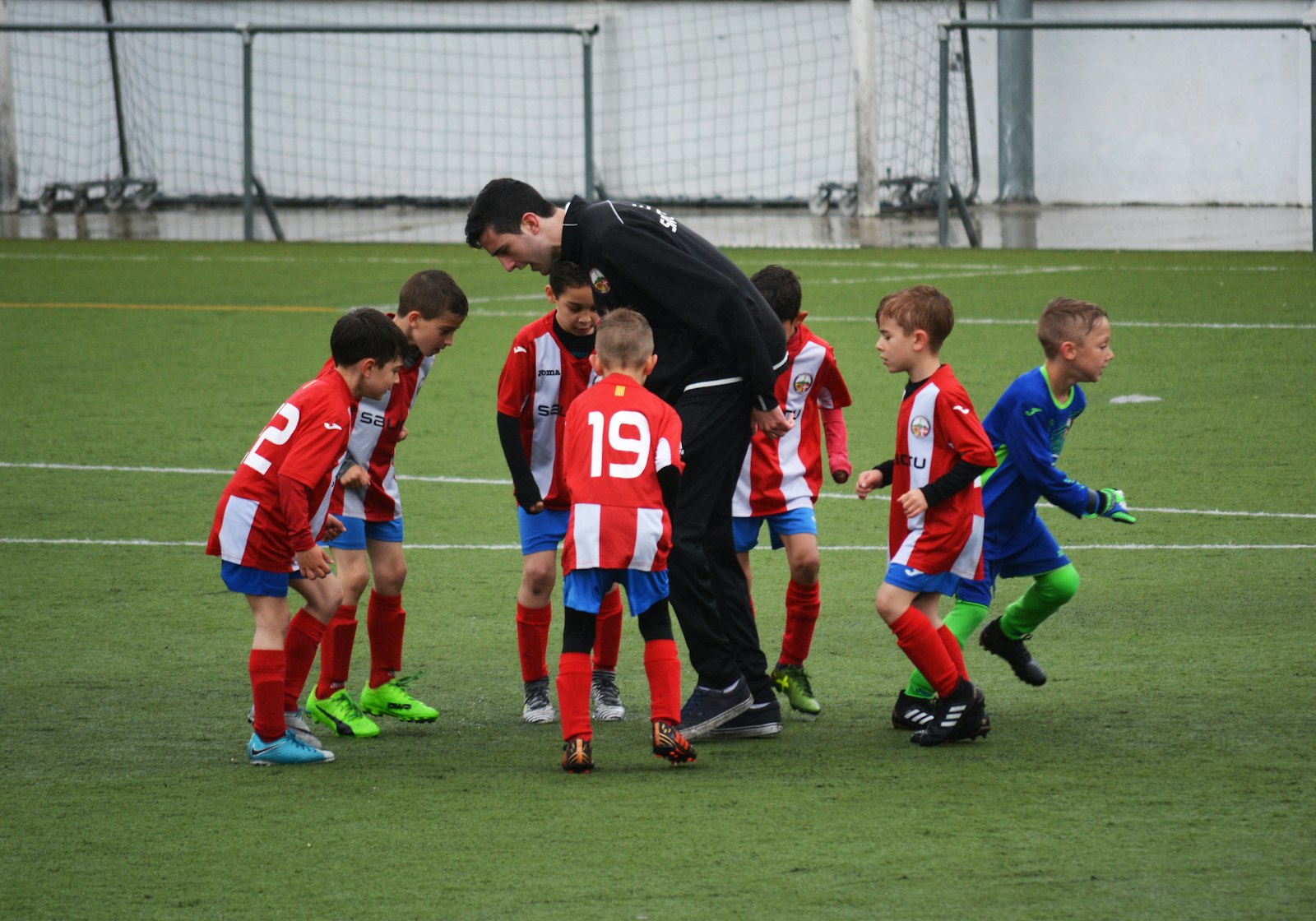 Youth soccer team huddled around their coach on the pitch